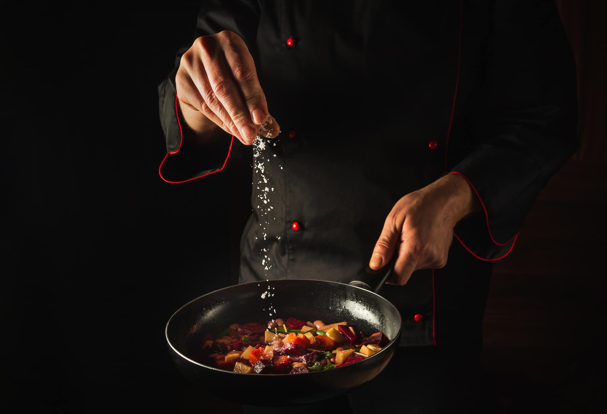 Cooking fried vegetables. The chef adds salt to a steaming hot pan. Menu idea for a hotel with advertising space. Asian cuisine. Cooking fried vegetables. The chef adds salt to a steaming hot pan. Menu idea for a hotel with advertising space. Asian cuisine